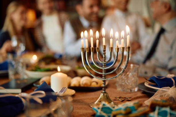 velas acesas em menorá com família judaica estendida ao fundo em chanucá. - hanukkah menorah judaism religion - fotografias e filmes do acervo