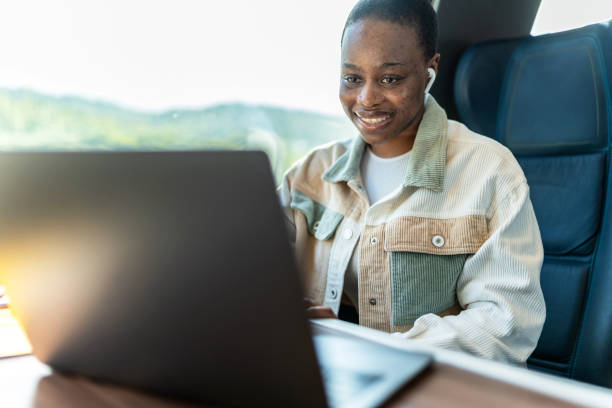 istock Cute African-American student using laptop on train, copy space on window, business travel or technology concept. 1756058896