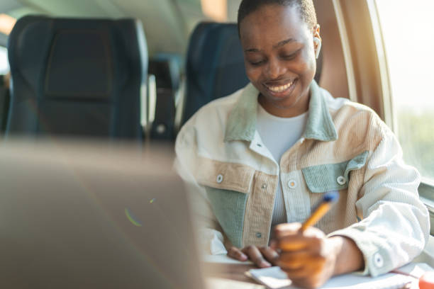 istock Cute African-American student using laptop on train, copy space on window, business travel or technology concept. 1756058902