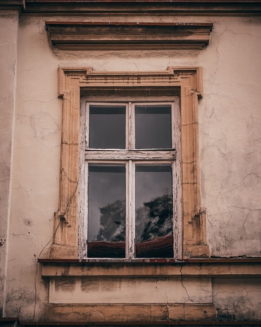 A close up shot of a window with a weathered wooden frame and peeling paint