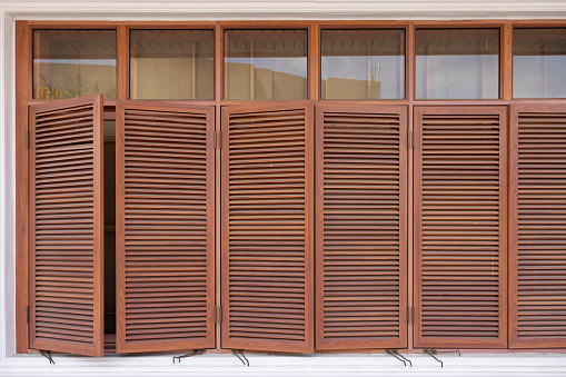 brown wood louvers or louvered shutters with glass windows on the wall.