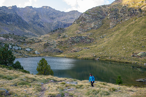 young caucasian girl walking towards the mountain after visiting the lake of tristaina in andorra among the mountains