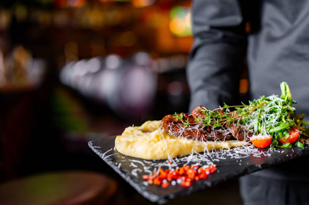 istock chef or waiter hold plate with beef Cheeks In Demiglas Sauce with mashed potatoes and salad 1756107269
