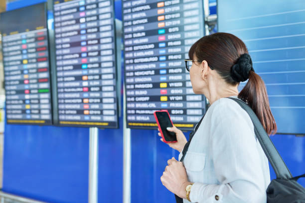 istock Woman passenger looking at flight schedule board at airport 1756129779