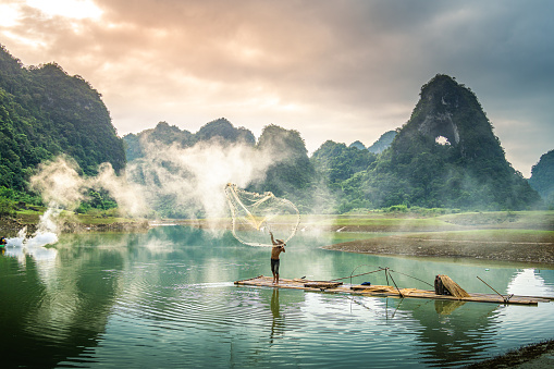 view of fishermen fishing on river in Thung mountain in Tra Linh, Cao Bang province, Vietnam with lake, cloudy, nature. Travel and landscape concept.