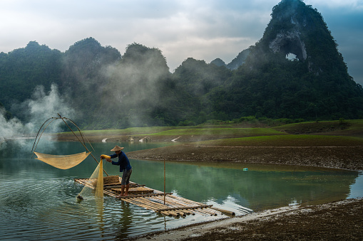 view of fishermen fishing on river in Thung mountain in Tra Linh, Cao Bang province, Vietnam with lake, cloudy, nature. Travel and landscape concept.
