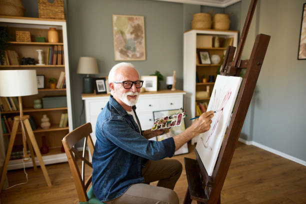 Elderly man painting on a canvas at home