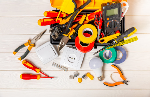 Electrician tools on background. Multimeter,construction tape,electrical tape, screwdrivers,pliers,an automatic insulation stripper, socket and LED lamp. Flatley. electrician concept.