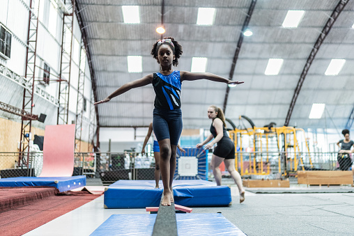 Girl walking on a balance beam in a gymnasium