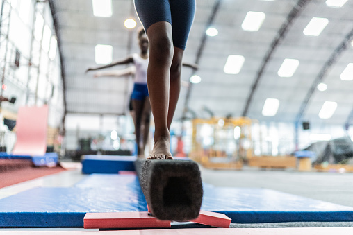 Low section of a girl walking on a balance beam in a gymnasium
