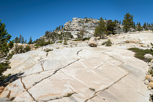 Hillside of fractured granite rock leading to the top of a mountain and clear blue sky in Yosemite National Park California during summer