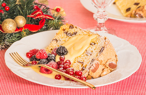 Panettone Italian Christmas sweet bread in plate and berries background.