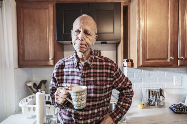 Senior man making morning coffee in his kitchen. He is dressed in casual clothes. Interior of private home in Toronto, Canada.