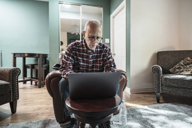 istock Senior man using laptop in his living room 1756189495