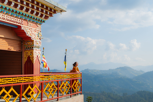 Woman standing on the balcony of Tibetan monastery  on the background of Himalaya mountains