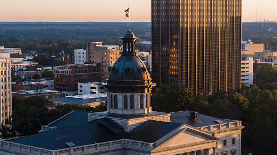 South Carolina State House dome with flags rising above the cityscape in the early morning. Downtown Columbia at dawn