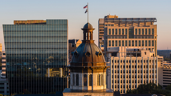 Architectural Dome with flags stands amidst downtown Columbia Office Buildings in SC: South Carolina State Capitol at dawn.