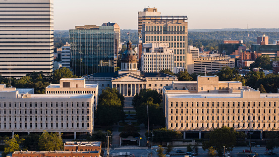 At dawn, the South Carolina State House stands in opposition to the skyscrapers of Downtown Columbia, SC.