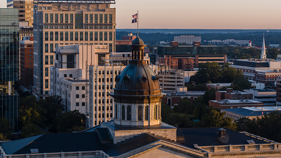 South Carolina State House dome with flags rising above the cityscape in the early morning. Downtown Columbia at dawn