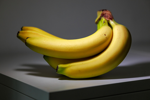 A bunch of bananas in light and shadow, captured in a studio shot