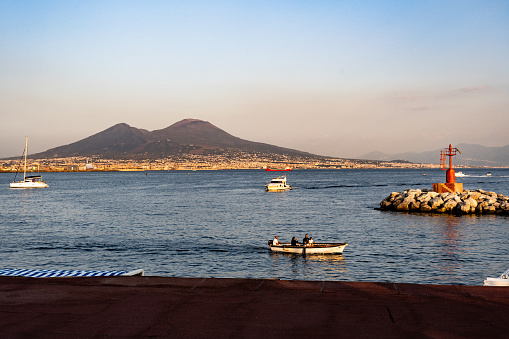 Naples, Italy - October 1, 2023: Vesuvius seen and fish boats from the seafront of Naples, Italy