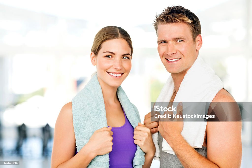 Young Couple With Towels Around Neck Smiling In Gym Portrait of smiling young couple with towels around neck after workout in gym. Horizontal shot. 20-24 Years Stock Photo