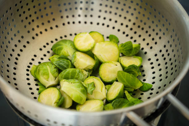 Brussels sprouts steaming in a sieve on top of the kettle, close up view.