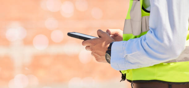 istock Hands of engineer on construction site, typing on phone and checking email for building schedule with mockup. Architecture, communication and business man with cellphone reading text, chat or report. 1756221567