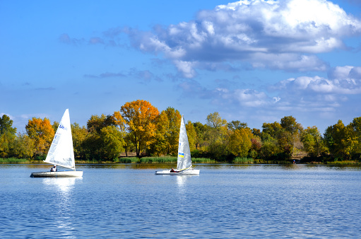 Two yachts on the Dnieper River against the backdrop of an autumn landscape.
