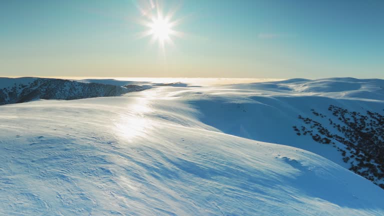 Aerial view snow breeze at mountain peak in sunrise