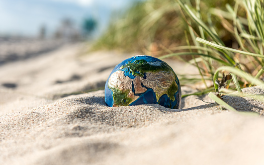 Planet Earth in the hot dunes of a beach. Conceptual image about global droughts as a result of climate change. Visual references from NASA (https://visibleearth.nasa.gov/images/74117/august-blue-marble-next-generation).