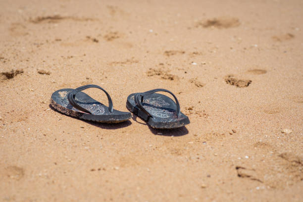 istock Black flip flops on the sand. 1756241204