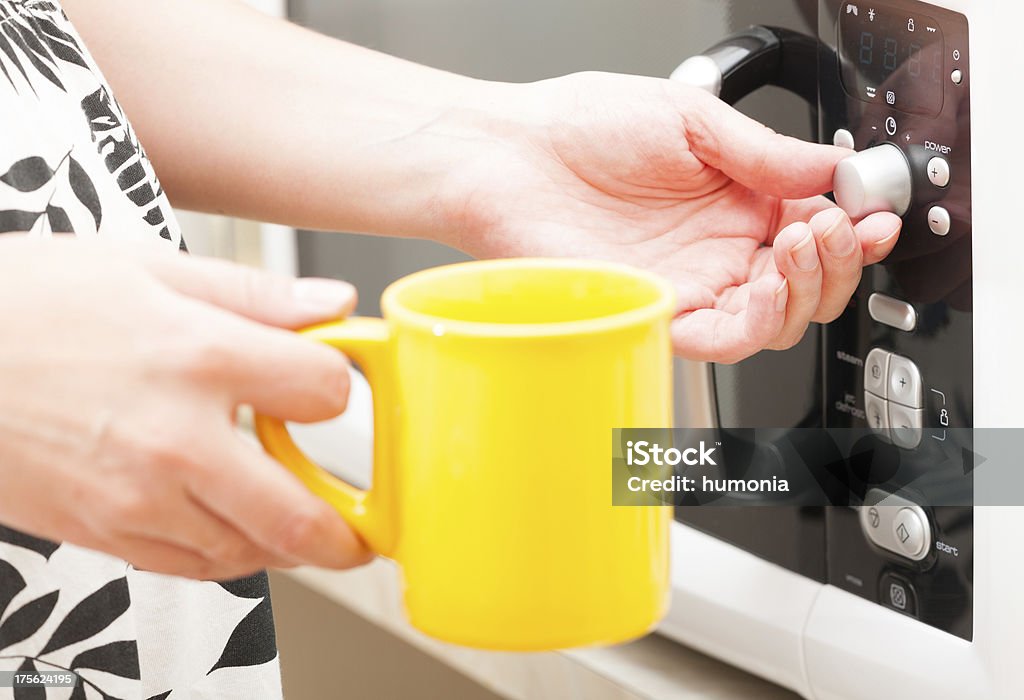 Setting a timer on the microwave oven Moving the timer knob on the microwave oven with mug in the other hand Microwave Stock Photo