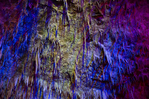 Karst cave, amazing view of stalactites and stalagnites in colorful bright light, beautiful natural landmark in touristic place.