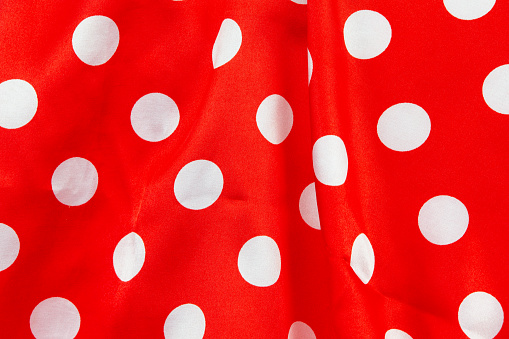 Background red satin fabric with white polka dots.