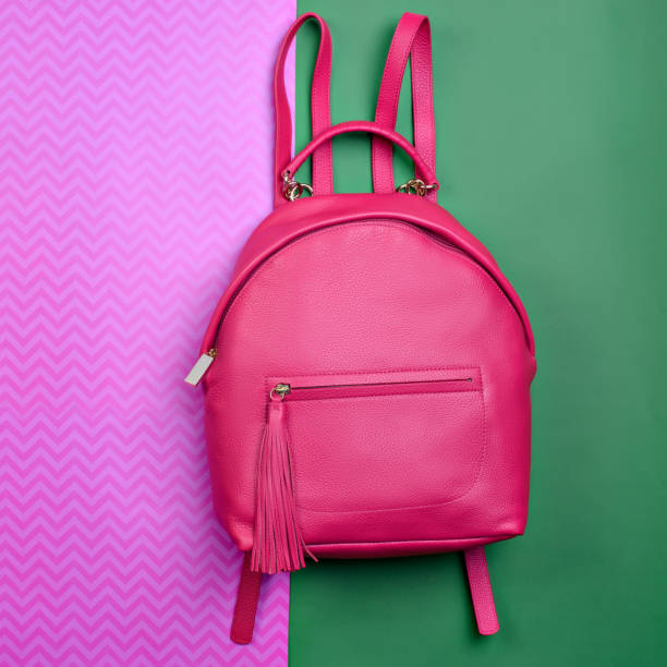 istock Contemporary women's pinkish-red leather backpack with a handle and zipped compartment with tassel pull isolated on a fun contrasting pink-green background. Mock-up for online fashion store or blog. 1756252336