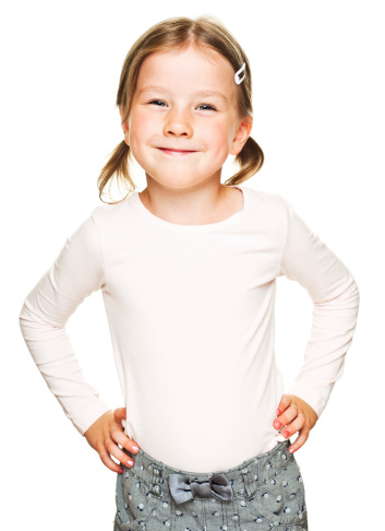 Portrait of cute little girl standing with hands on hip and smiling at the camera. Studio shot, isolated on white.