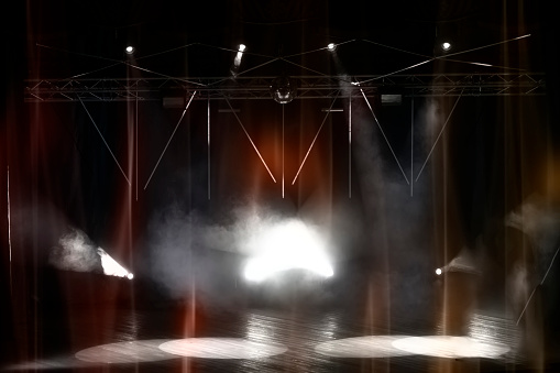 Stage lighting with laser illumination and puffs of smoke. Dark stage background.