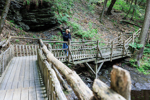 Mature woman, tourist hiking through Bushkill Falls, PA. Taking photos at Pocono Mountains in Pennsylvania