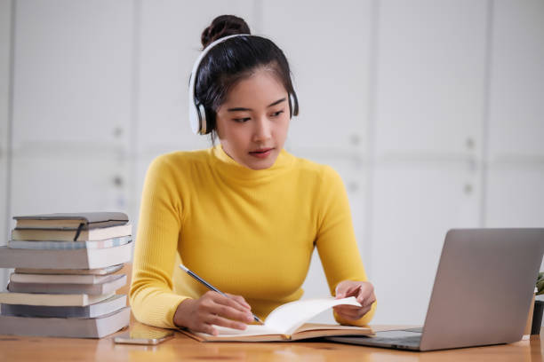 istock Young adult asian student woman taking notes while using laptop computer at home. Asian female learning online listening virtual video call. Business and education concept. 1756262847