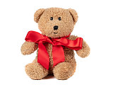 Toy fluffy vintage bear with a red bow on a white background. Brown teddy bear isolated.