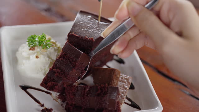 Close up of hand taking bite slice of chocolate cake  with fork.