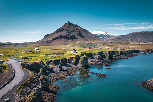 Beautiful view of Arnarstapi fishing village with nordic house and stapafell mountain by basalt rocks formation on coastline in Snaefellsnes peninsula at Iceland