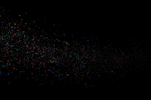 Glittering multi colored stardust on black background