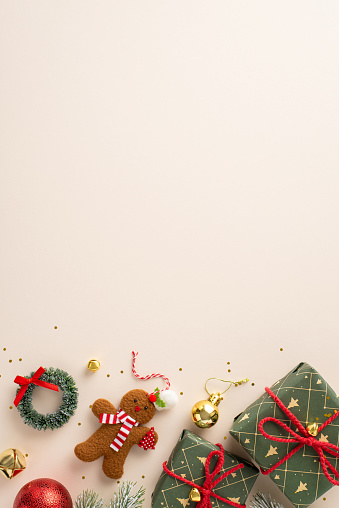 A festive tableau: Overhead vertical view of wrapped gifts, vivid baubles, gingerbread man decor, jingling bells, petite wreath, shiny confetti on a light canvas with ad space