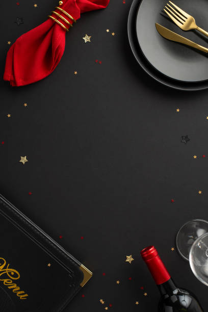 istock Upscale restaurant Black Friday sale theme. Vertical top view of table setup showcasing dinnerware, napkin, menu book, wine bottle, glass, glitzy confetti on black backdrop with space for text or ad 1756315877