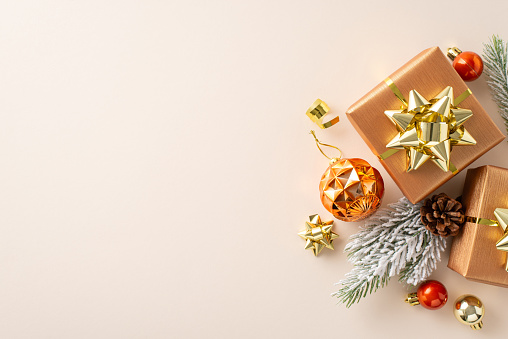 Get ready for the holidays! A top-view snapshot of gift boxes adorned with star ribbon bows, orange and gold balls, cone, and frost-kissed fir twigs on cozy beige surface, awaiting your holiday wishes