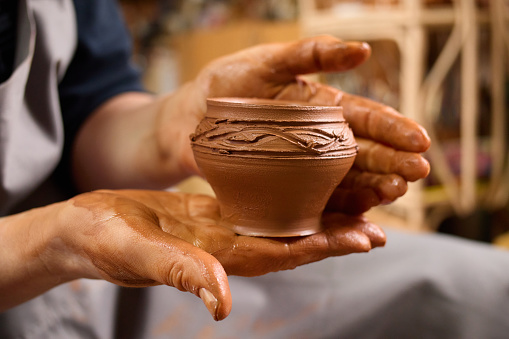 Art workshop. Wet clay. Traditional craft. Molding closeup. Handcrafted bowl. Creative master. Potter's hands gently and surely formed by clay pot on potter's wheel.