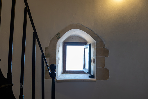 Interior of Gavdos Lighthouse, Crete island Greece. Outdoors view through an open small window in front of metal ladder. Illuminated wall