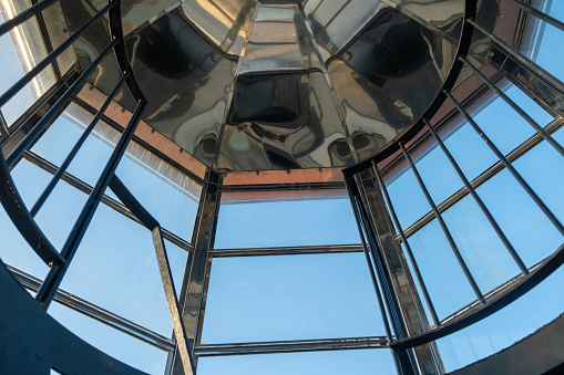 Interior top of Gavdos Lighthouse, Crete island Greece. Under view from ladder end of metal reflective frame construction and blue sky.